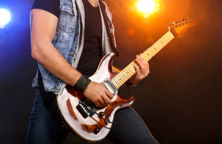 uomo suona la chitarra sul palco